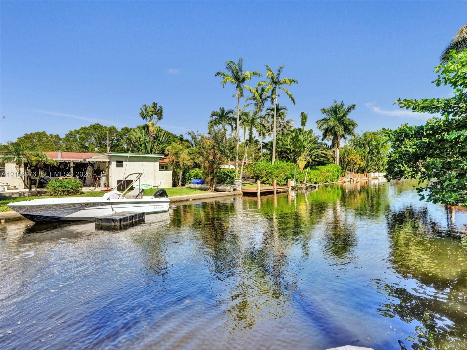 525 SW 12th Street, Fort Lauderdale, Fort Lauderdale, FL 33315 Waterfront property featuring a private wooden dock, bulkhead sea wall, and mature palm trees