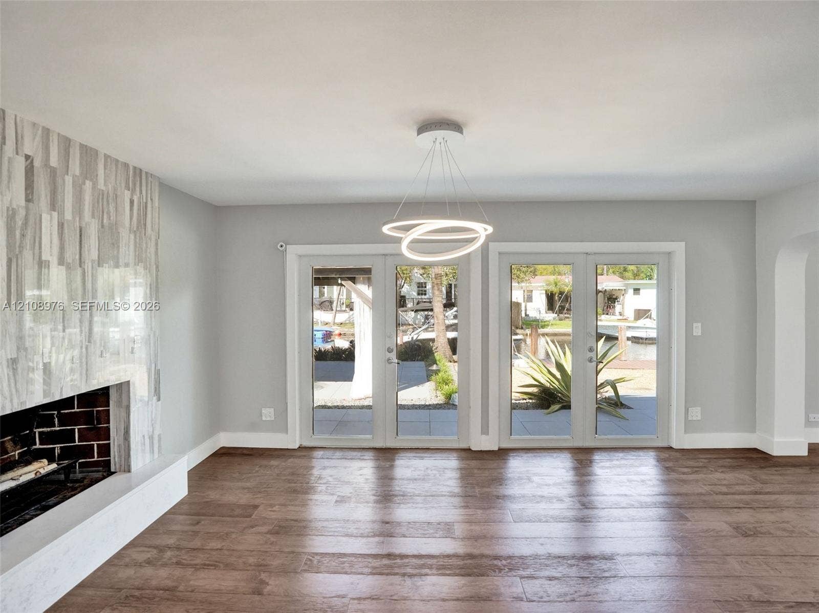 525 SW 12th Street, Fort Lauderdale, Fort Lauderdale, FL 33315 Living area featuring wood-finish flooring, a contemporary circular pendant light fixture, and dual sets of glass-paned doors