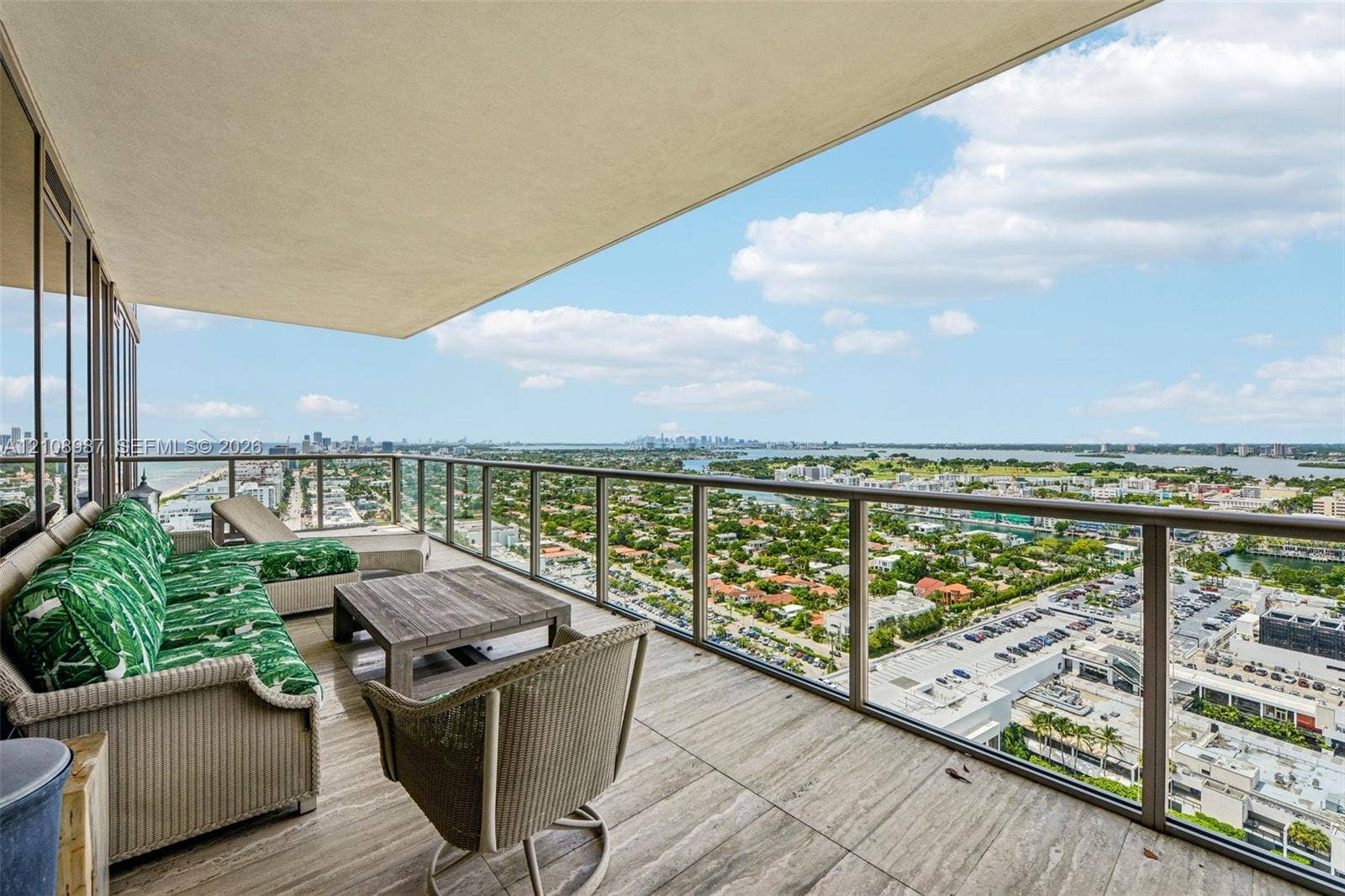 Expansive covered balcony featuring large-format stone tile flooring and glass panel railings