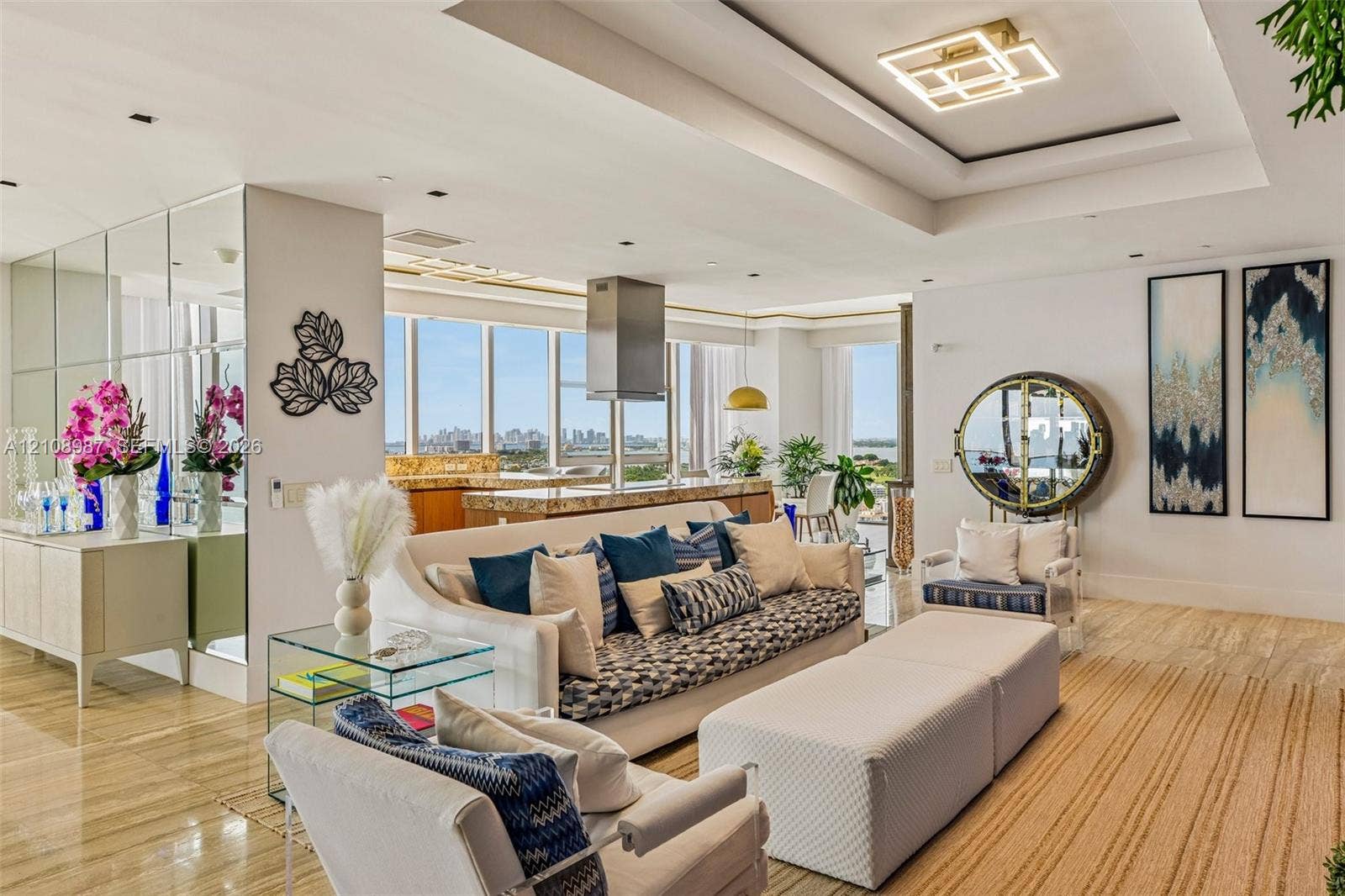 Open-concept living space featuring floor-to-ceiling windows, polished stone flooring, recessed tray ceilings with geometric lighting, and mirrored wall accents