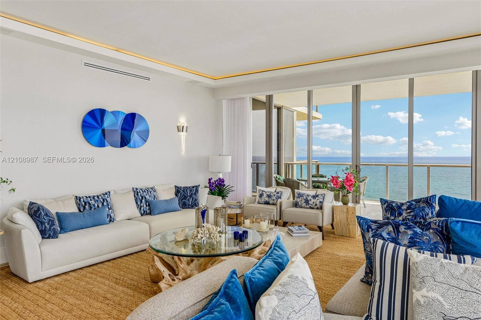 Living area featuring floor-to-ceiling glass sliding doors, recessed tray ceiling lighting, and integrated wall sconces