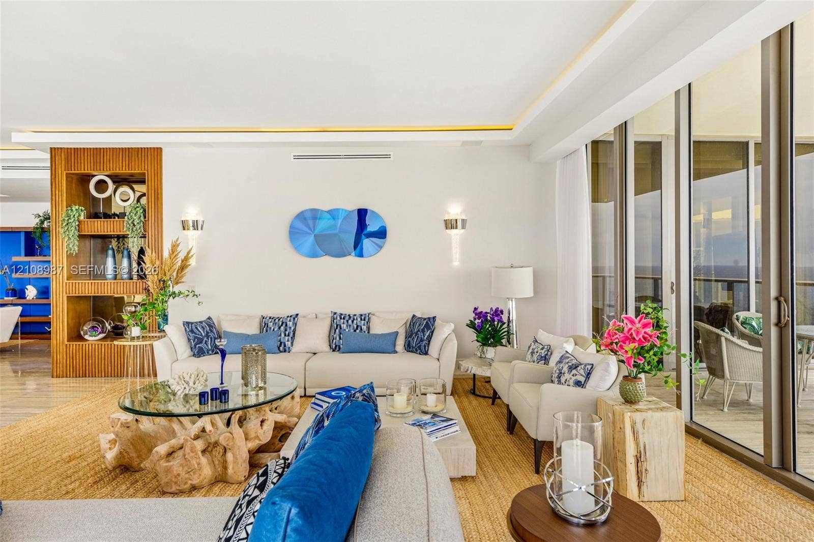 Full-height sliding glass doors, recessed ceiling lighting with crown molding detail, built-in floor-to-ceiling wood shelving, and polished stone-finish flooring