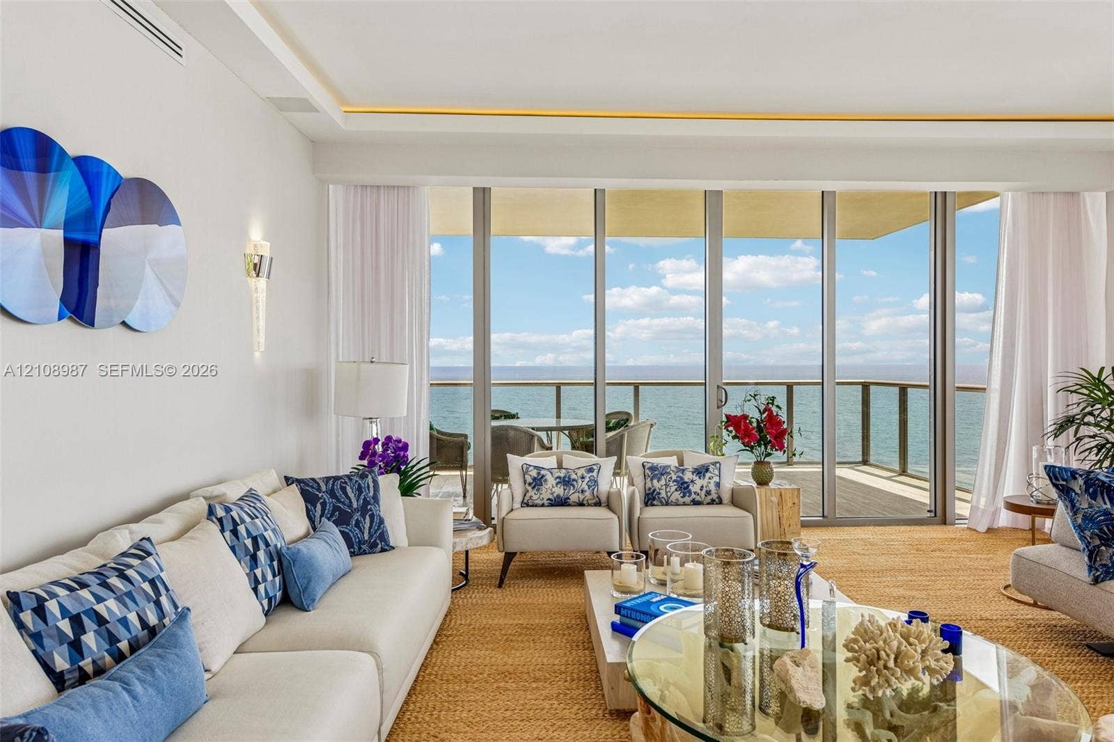 Floor-to-ceiling glass sliding doors, recessed ceiling lighting, wall-mounted sconce, and spacious exterior balcony with metal railing