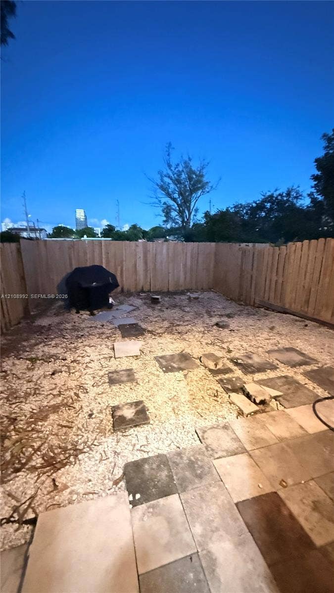 Rear exterior featuring a wood fence, paver patio, and stone ground cover
