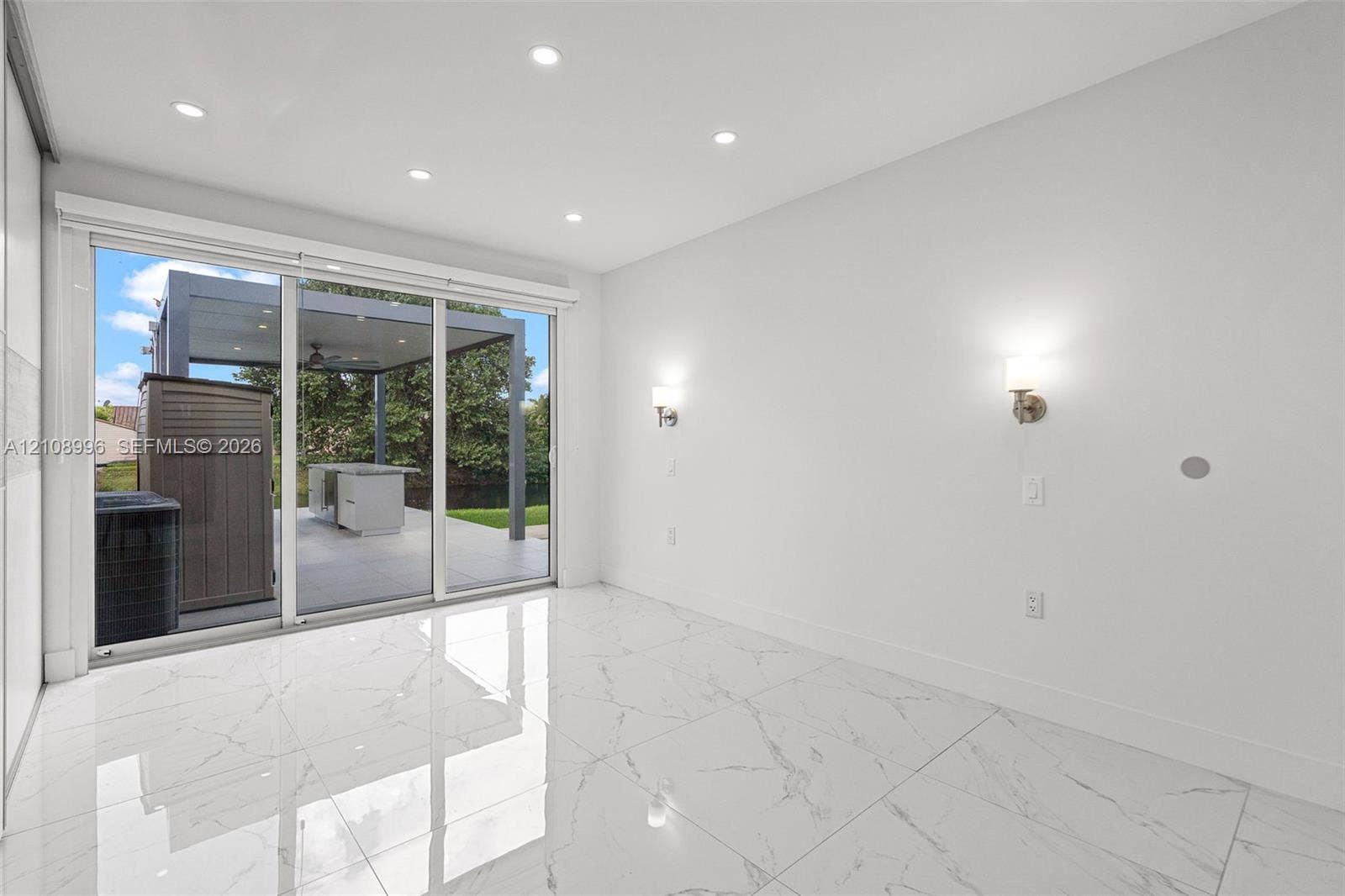 4252 SW 131st Avenue, Miami, FL 33175 Large-format tile flooring with marble-style veining, recessed ceiling lighting, wall-mounted sconces, and sliding glass doors