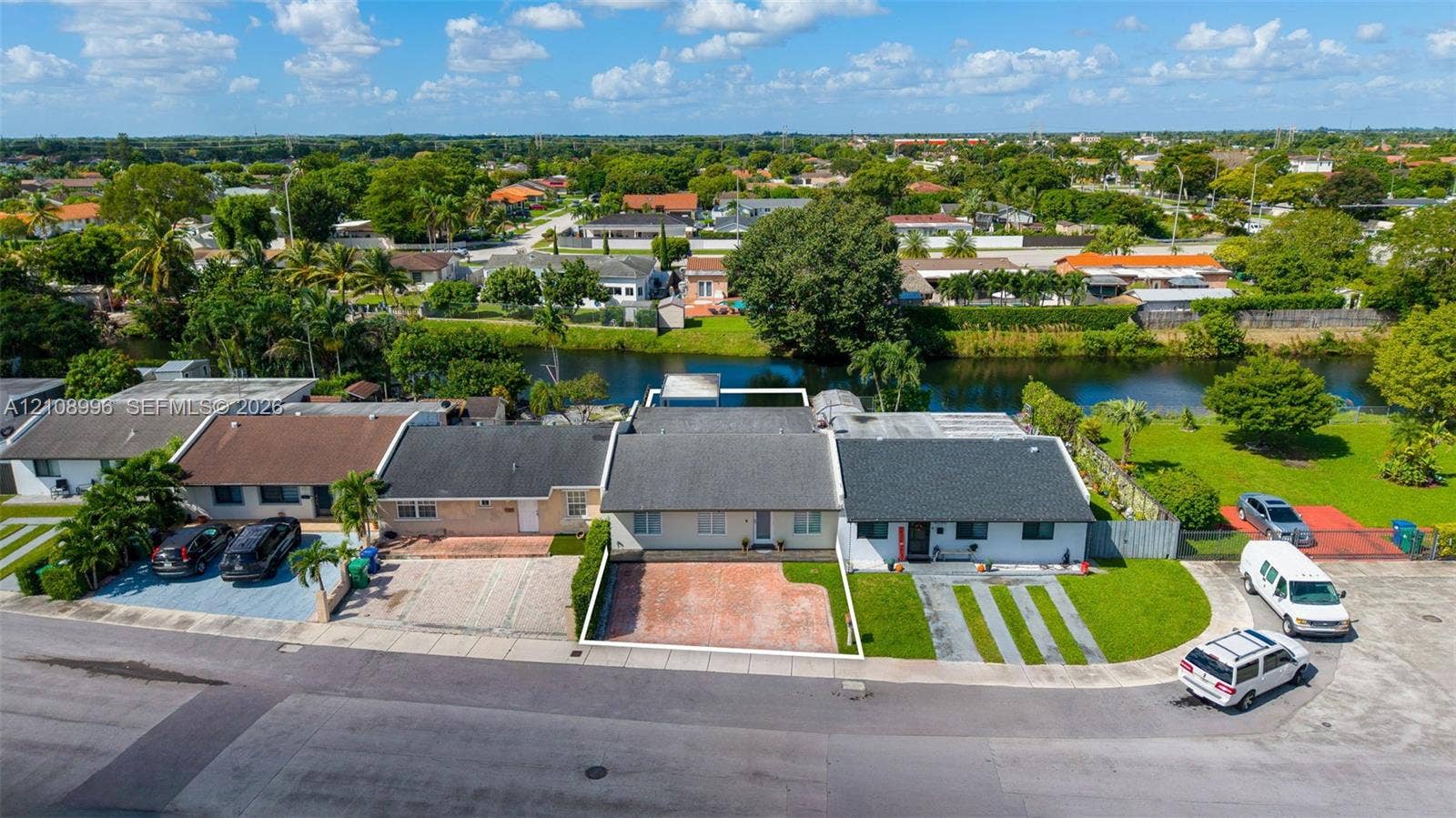 4252 SW 131st Avenue, Miami, FL 33175 Aerial perspective of a single-story residence featuring a shingled roof, a paved front courtyard, and direct canal frontage with a manicured rear lawn