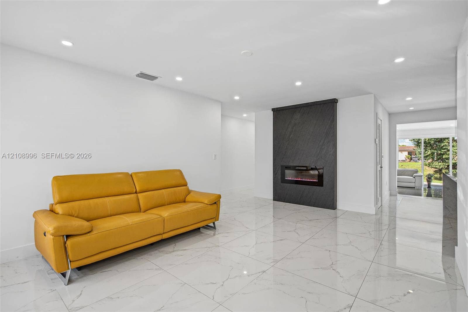 4252 SW 131st Avenue, Miami, FL 33175 Large-format stone-style flooring, recessed lighting, and a focal wall featuring a built-in linear electric fireplace