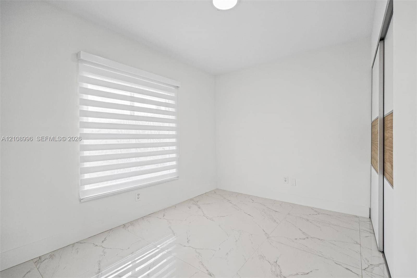 4252 SW 131st Avenue, Miami, FL 33175 Large-format white tile flooring with veining, dual-panel sliding closet with wood-finish inlay, and adjustable window roller shades
