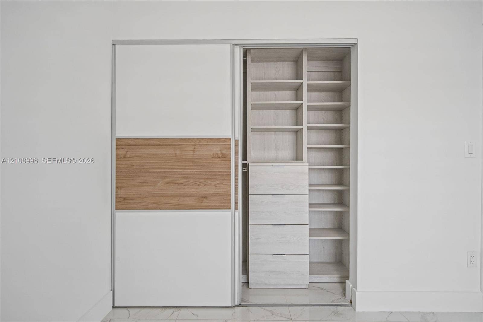 4252 SW 131st Avenue, Miami, FL 33175 Built-in closet featuring sliding doors with wood-finish accents, custom shelving, and a four-drawer storage unit