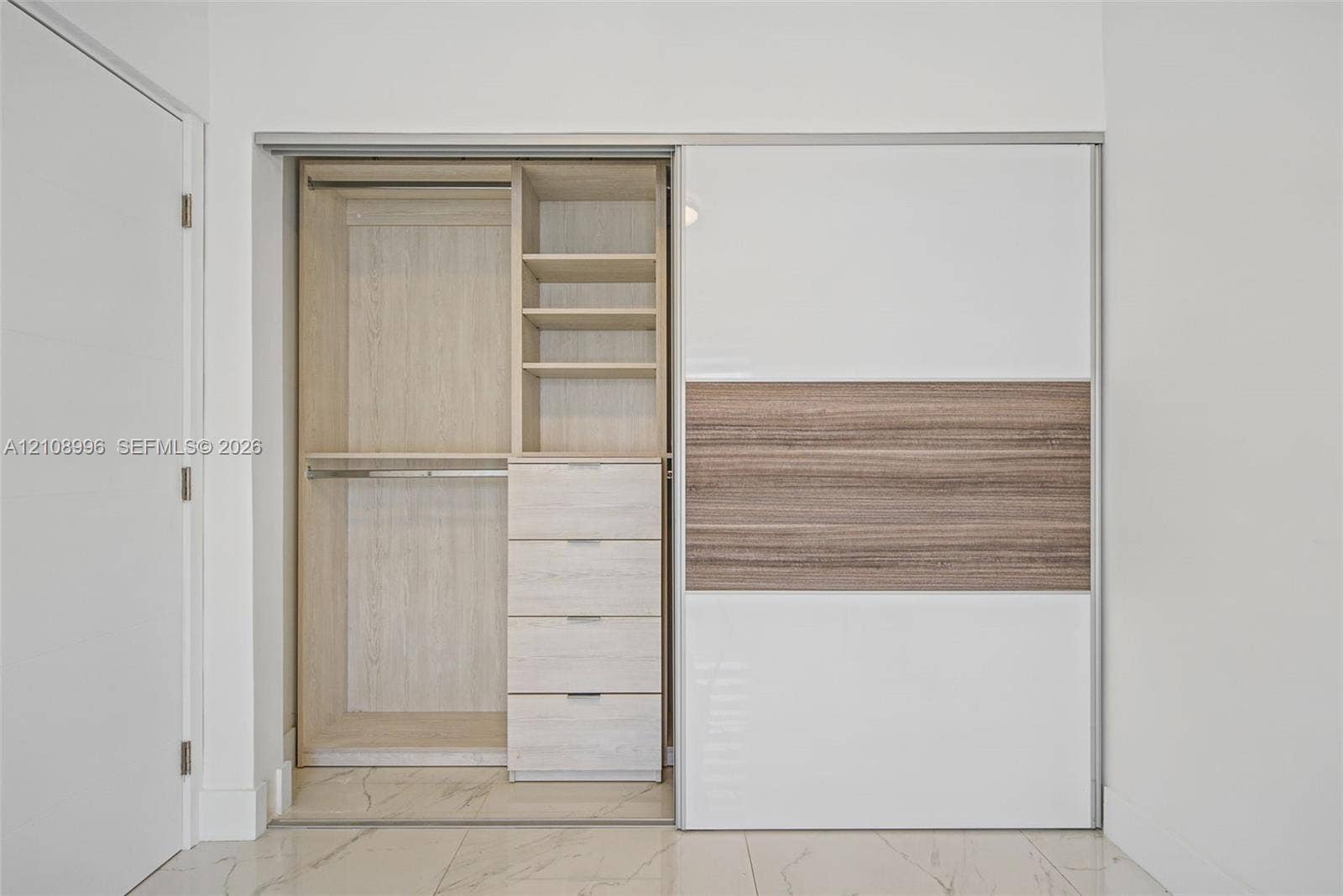 4252 SW 131st Avenue, Miami, FL 33175 Built-in closet featuring floor-to-ceiling sliding panels, integrated wood-finish shelving, four soft-close drawers, and metal hanging rods