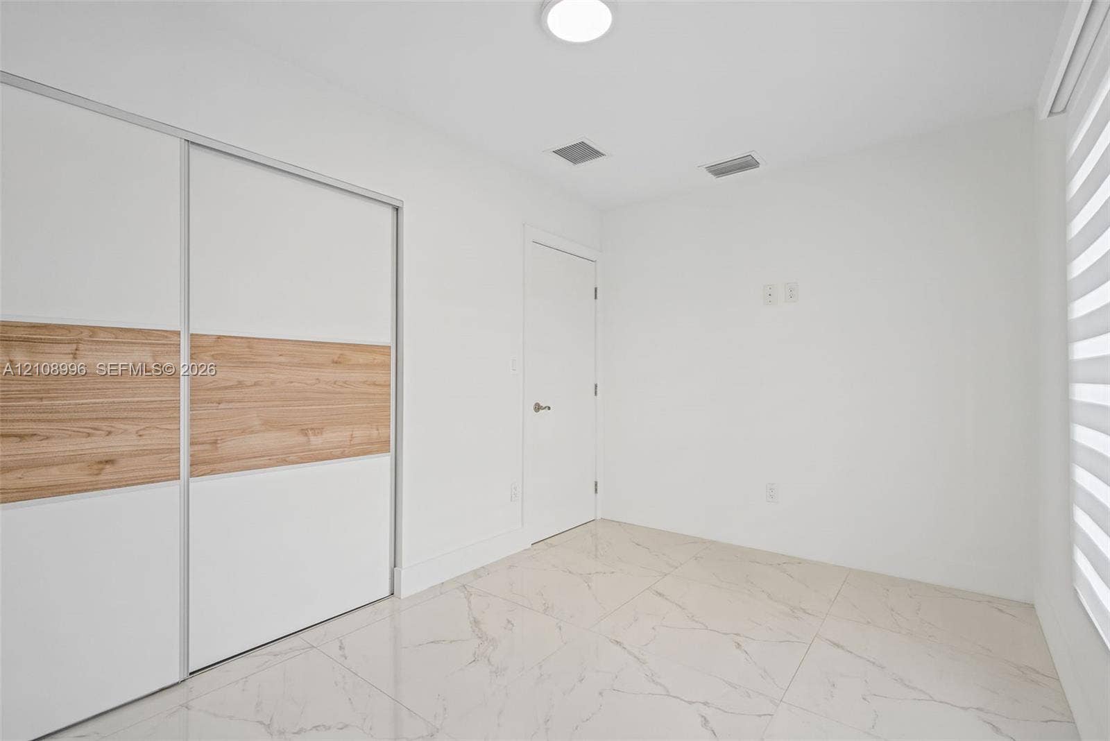 4252 SW 131st Avenue, Miami, FL 33175 Large-format tile flooring with veining, sliding closet doors with wood-finish accents, and layered window shades