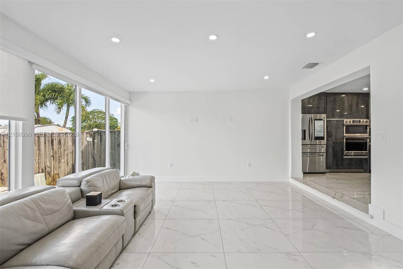 4252 SW 131st Avenue, Miami, FL 33175 Large-format porcelain tile flooring, recessed ceiling lighting, and expansive floor-to-ceiling windows featuring exterior greenery