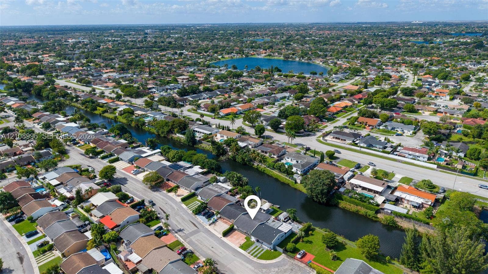 4252 SW 131st Avenue, Miami, FL 33175 Aerial perspective of a single-story residence featuring a concrete tile roof, paved driveway, and direct water frontage along a canal