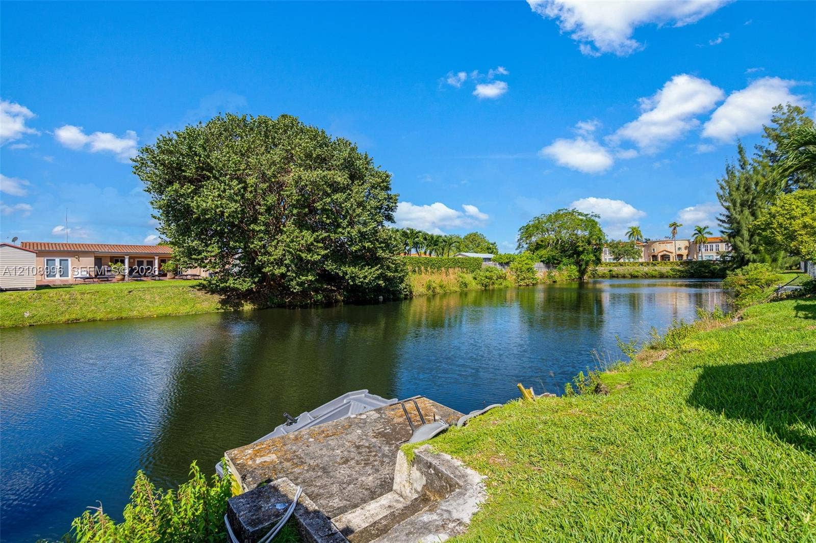 4252 SW 131st Avenue, Miami, FL 33175 Waterfront parcel featuring a concrete bulkhead, private stair access to the canal, grassy lawn, and mature trees