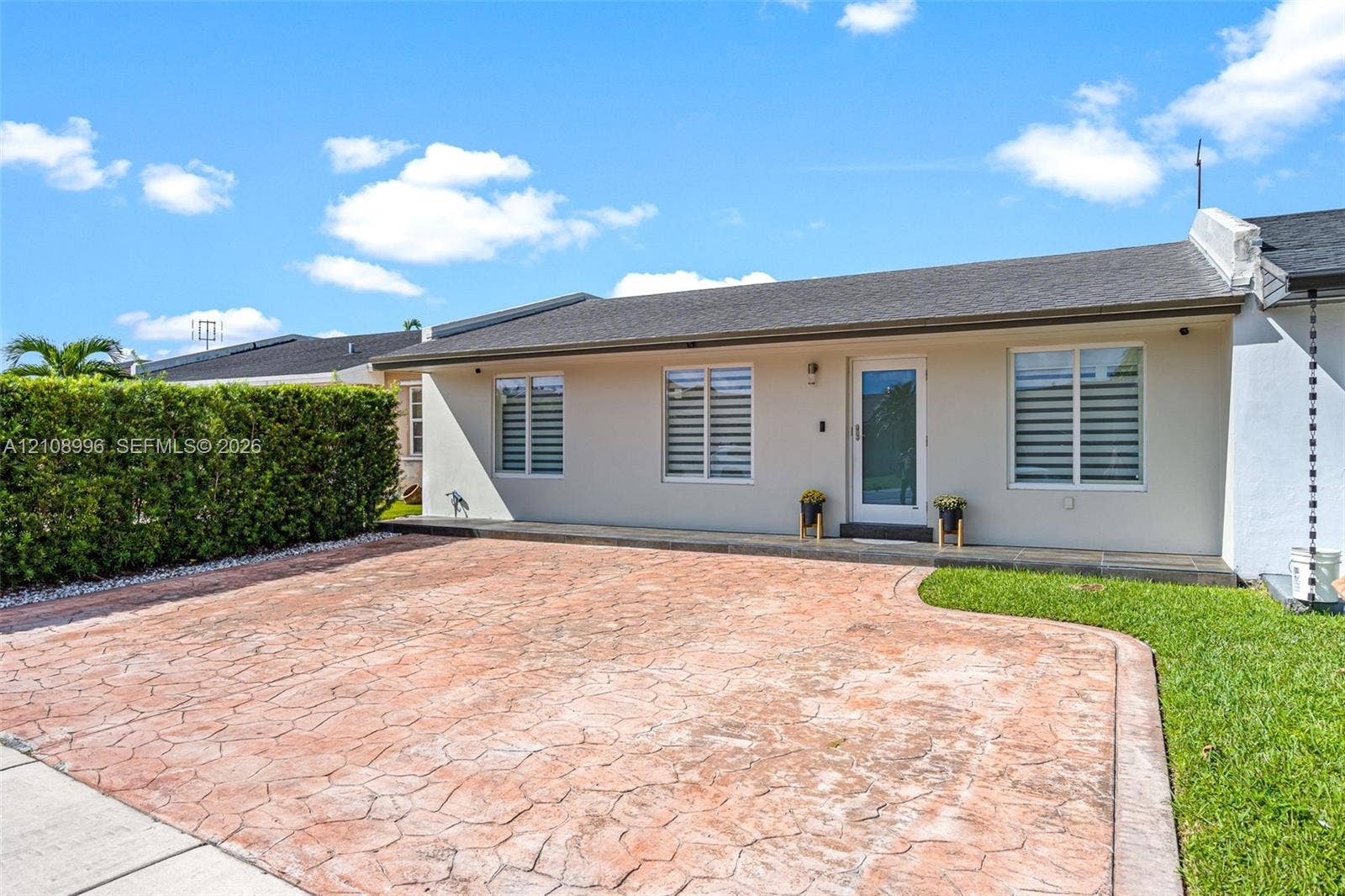 4252 SW 131st Avenue, Miami, FL 33175 Single-story exterior featuring a stamped concrete driveway, exterior light fixture, horizontal sliding windows, and a manicured hedge