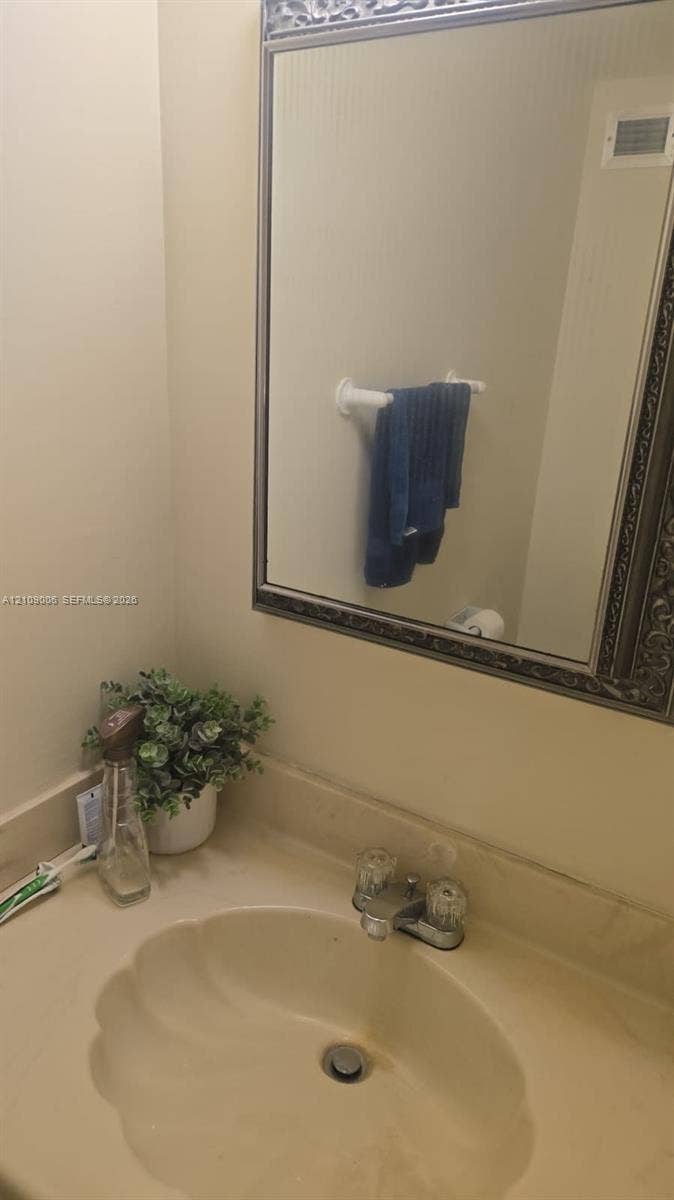 Wall-mounted mirror with decorative metallic frame, integrated countertop sink, and dual-knob faucet