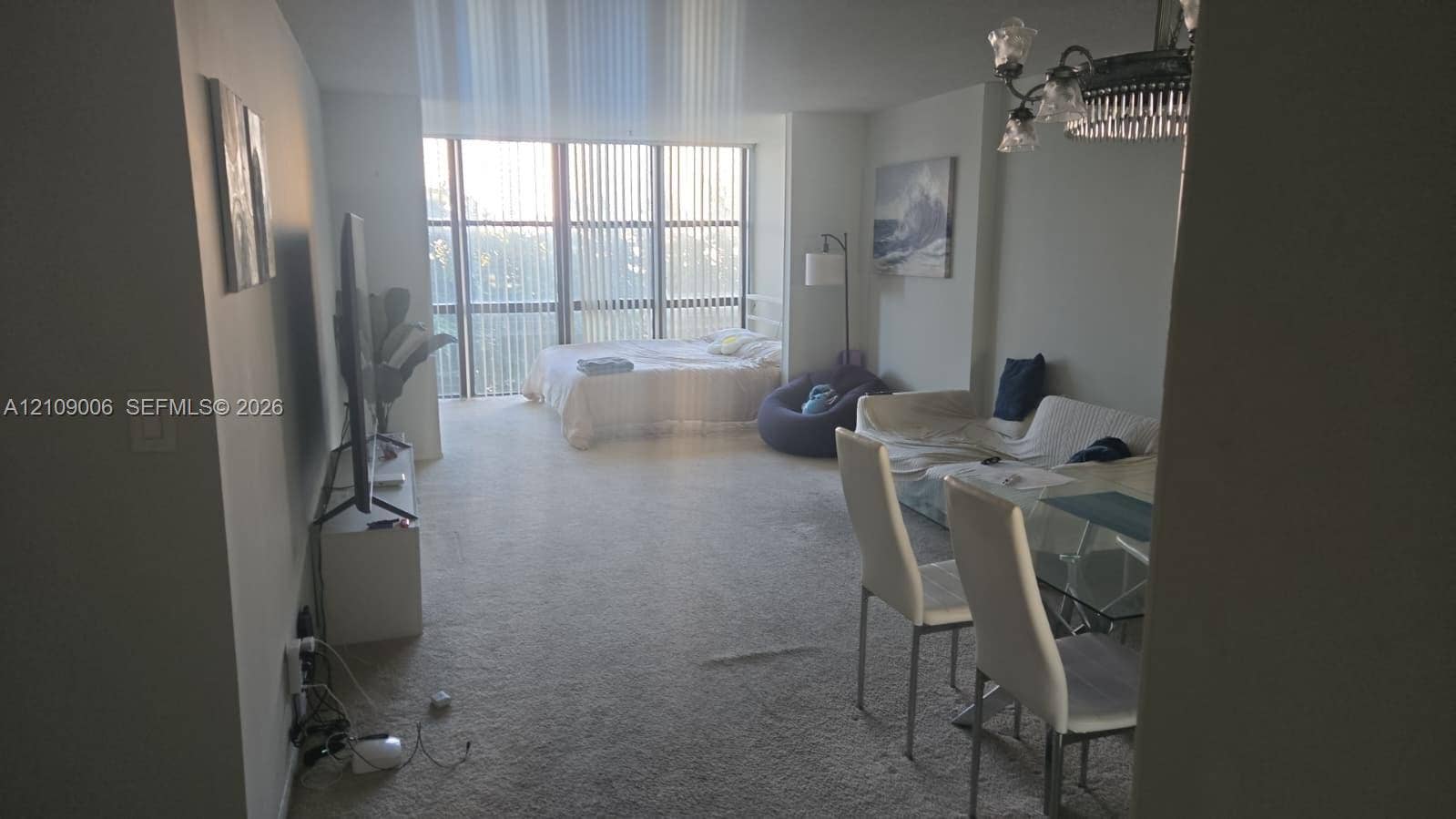 Floor-to-ceiling windows with vertical blinds and a traditional multi-arm chandelier