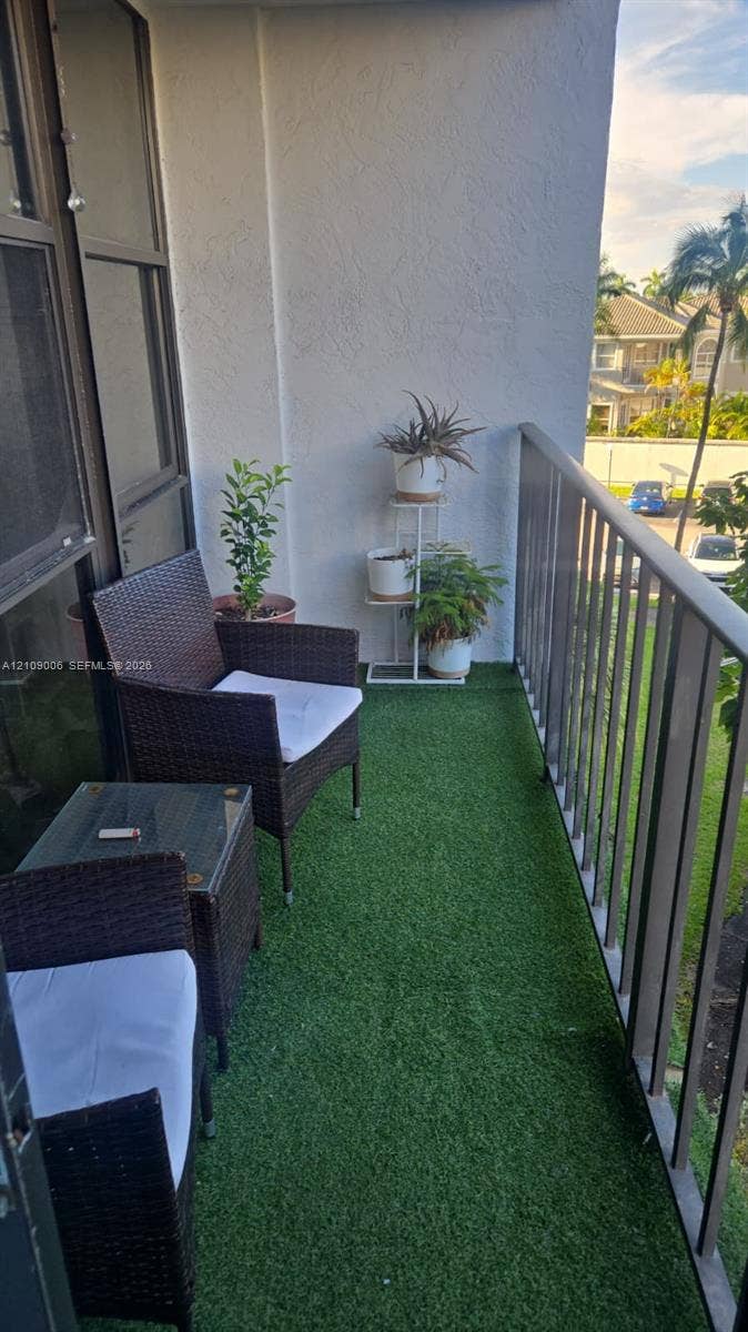 Covered balcony featuring artificial turf flooring, a metal railing, and textured wall finishes