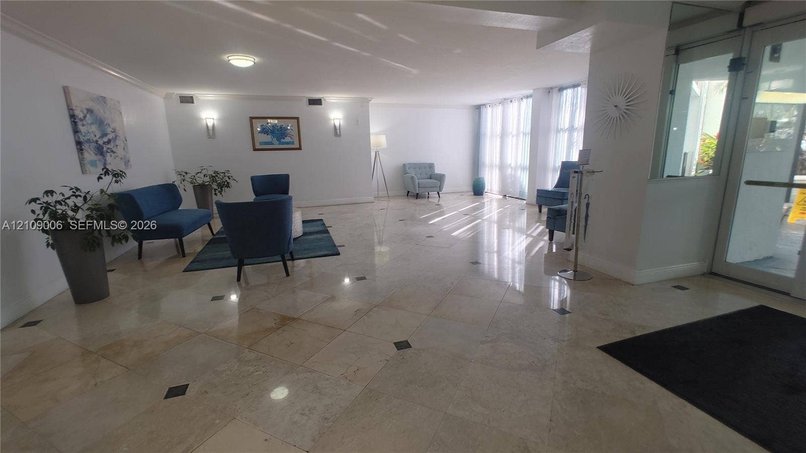 Polished stone flooring with decorative inlay accents, expansive floor-to-ceiling windows, and wall-mounted sconce lighting