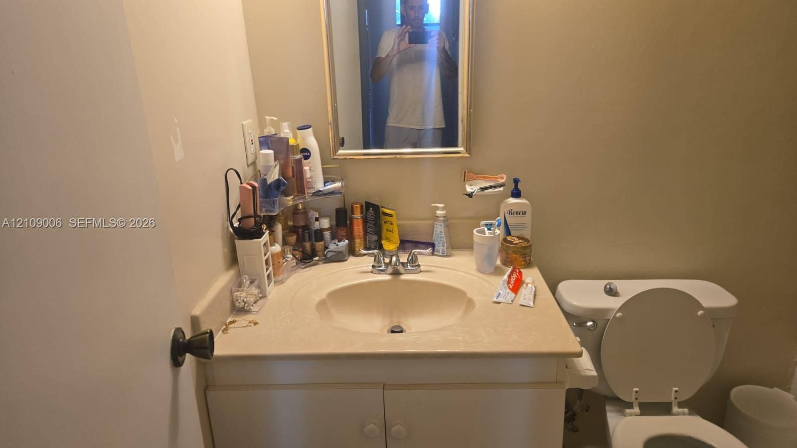 Vanity featuring an integrated sink, solid surface countertop, lower storage cabinetry, and a framed wall-mounted mirror