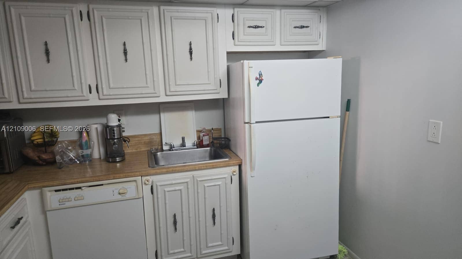 Kitchen area featuring white cabinetry, a top-mount stainless steel sink, a laminate countertop, and an integrated dishwasher