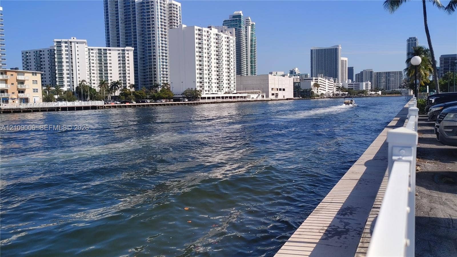 Waterfront bulkhead featuring a white metal perimeter railing and paved walkway