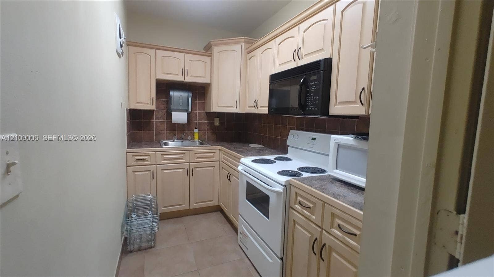 Kitchen featuring light-finish cabinetry, tile backsplash, built-in microwave, and tile flooring