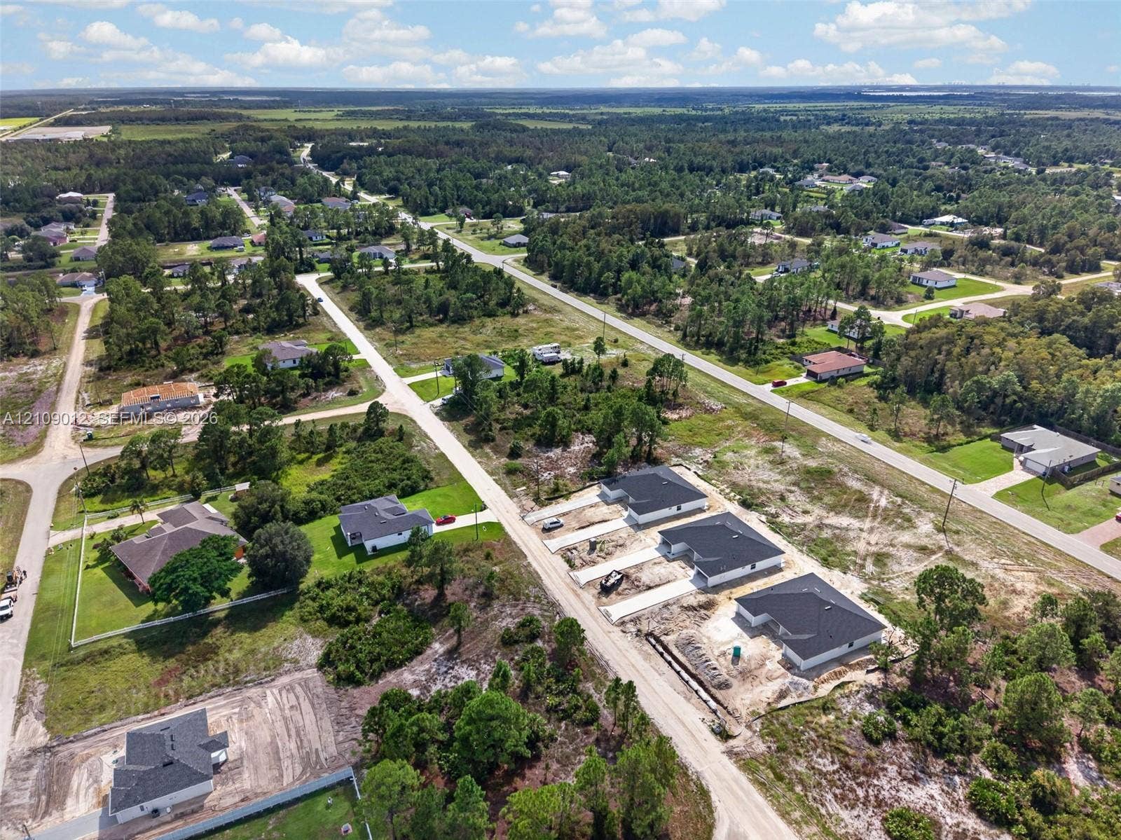 846 Burns Avenue S, Lehigh Acres, Lehigh Acres, FL 33974 Aerial perspective of a residential development featuring paved roadways, single-family structures, and cleared lots surrounded by dense tree lines