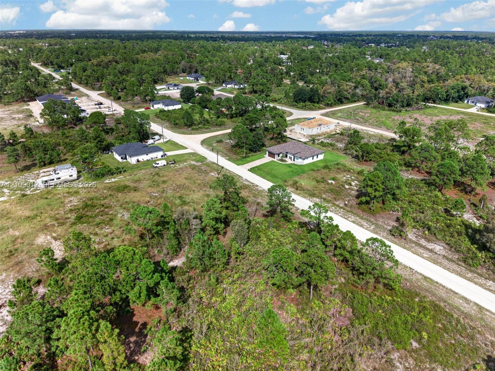 846 Burns Avenue S, Lehigh Acres, Lehigh Acres, FL 33974 Aerial perspective of a vacant lot featuring mature vegetation, native trees, and direct access to a paved thoroughfare
