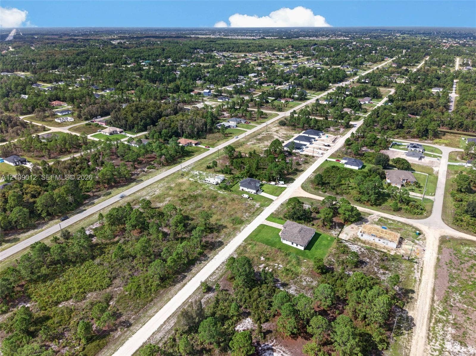 846 Burns Avenue S, Lehigh Acres, Lehigh Acres, FL 33974 Aerial perspective of a corner lot situated in a low-density residential area, featuring native vegetation and direct access to paved and unpaved roadway infrastructure