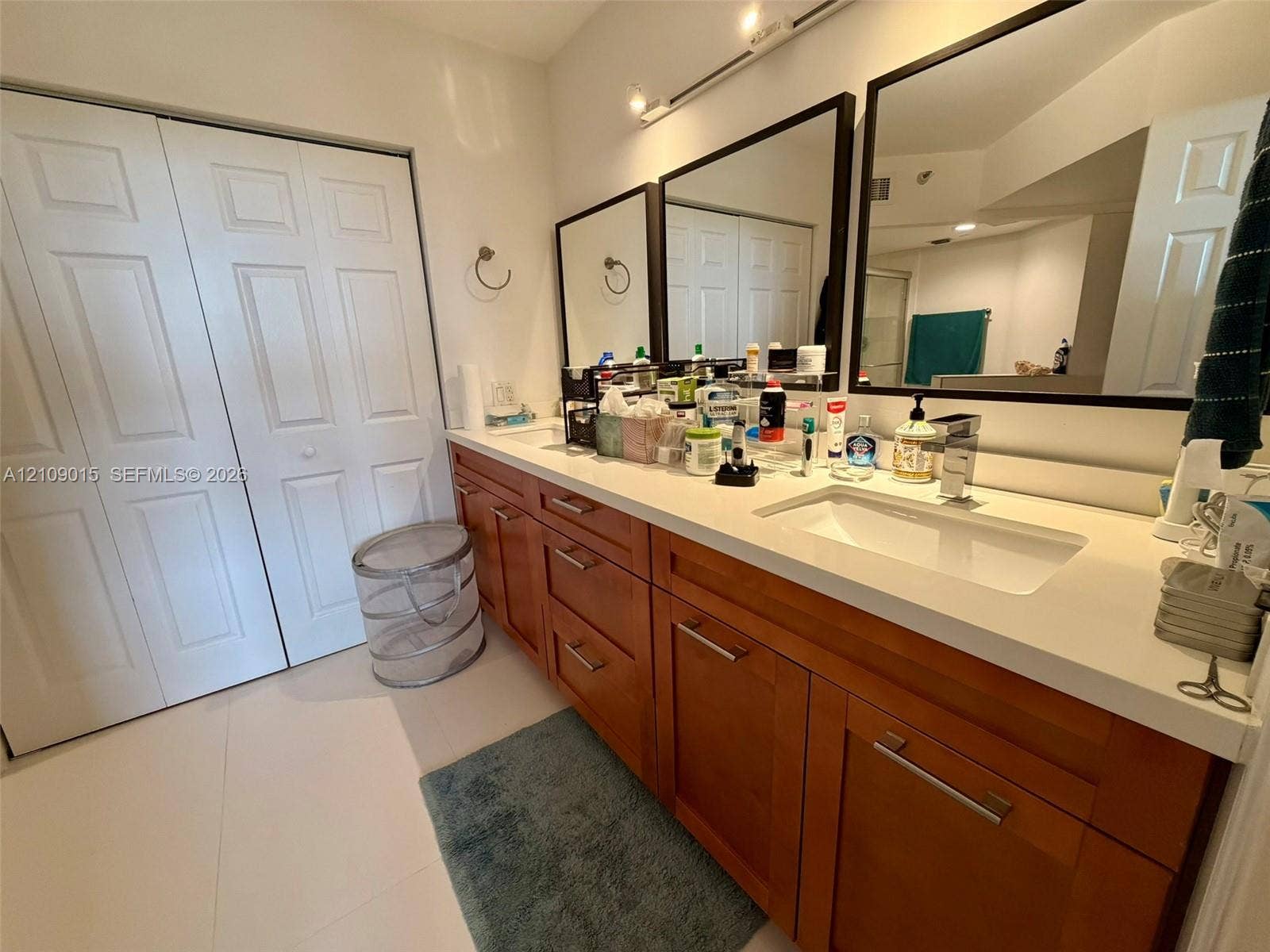 3530 Mystic Pointe Drive, #1709, Aventura, FL 33180 Extended wood-finish vanity with a stone countertop, dual integrated rectangular sinks, modern chrome fixtures, and three framed vanity mirrors