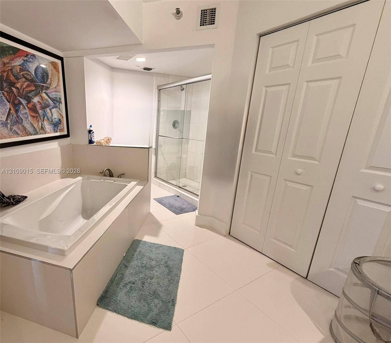 3530 Mystic Pointe Drive, #1709, Aventura, FL 33180 Bathroom featuring a drop-in soaking tub, a glass-enclosed shower, large-format tile flooring, and dual bi-fold closet doors