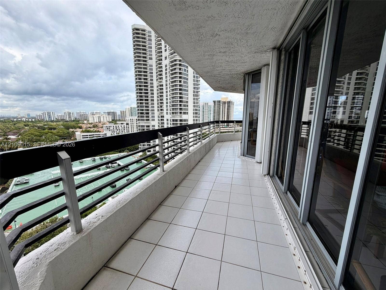 3530 Mystic Pointe Drive, #1709, Aventura, FL 33180 Spacious balcony featuring tile flooring, a horizontal metal railing, and floor-to-ceiling glass sliding doors