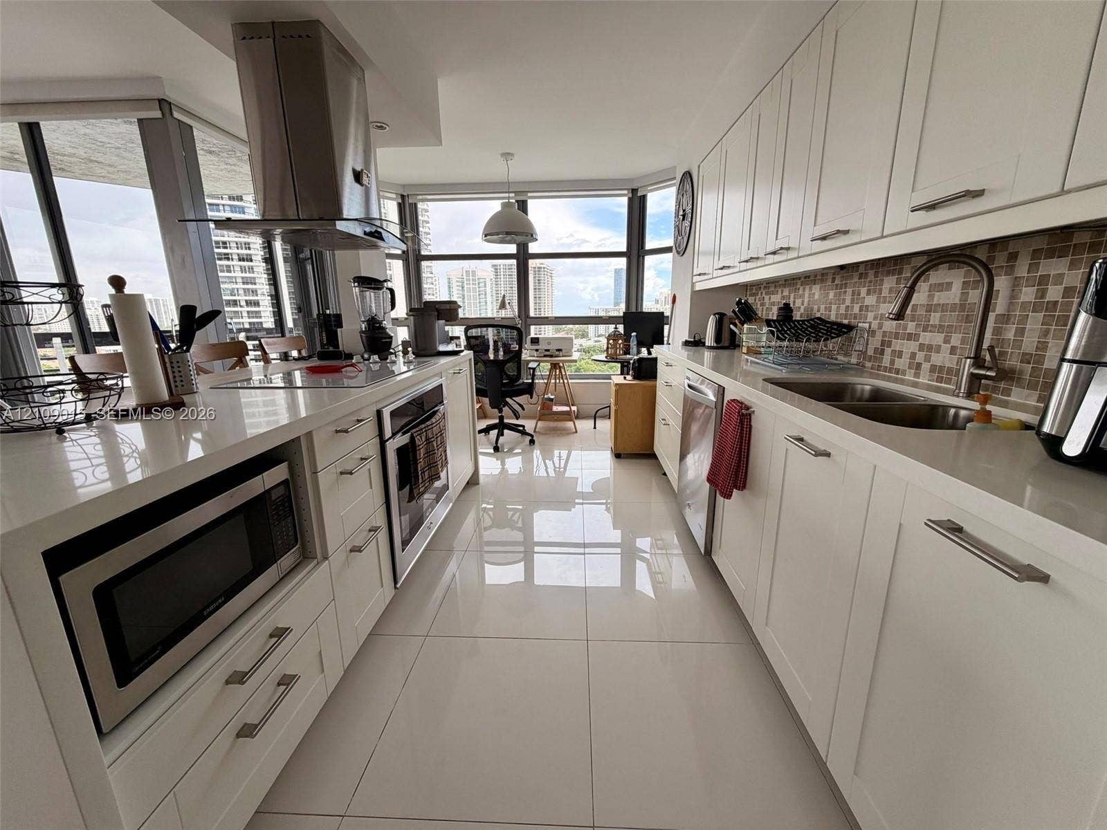 3530 Mystic Pointe Drive, #1709, Aventura, FL 33180 Kitchen featuring white cabinetry, quartz countertops, stainless steel appliances, a mosaic tile backsplash, and large-format porcelain floor tiling