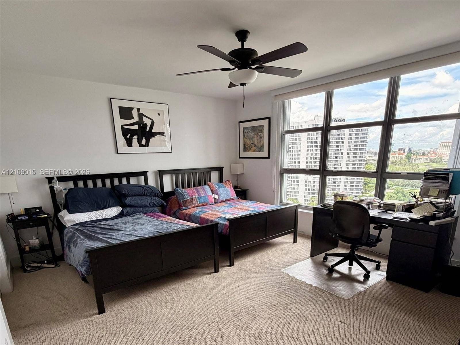 3530 Mystic Pointe Drive, #1709, Aventura, FL 33180 Bedroom featuring neutral carpeting, floor-to-ceiling windows with grid framing, and a matte black ceiling fan with integrated lighting