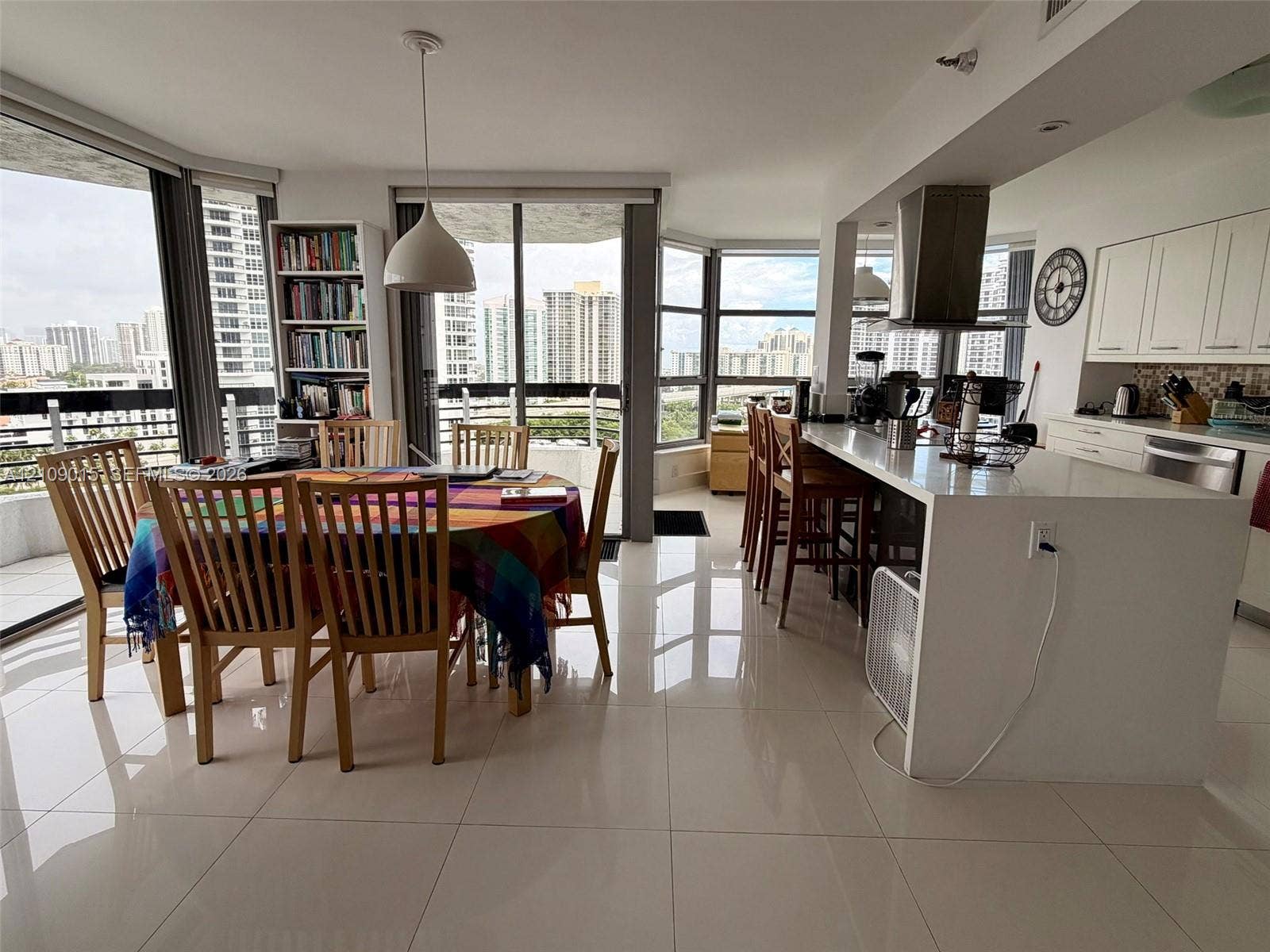 3530 Mystic Pointe Drive, #1709, Aventura, FL 33180 Open-concept interior featuring large-format tile flooring, floor-to-ceiling windows, white cabinetry, a quartz waterfall-edge kitchen island, and a stainless steel range hood