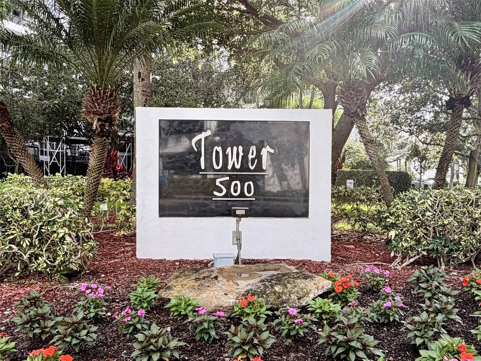 3530 Mystic Pointe Drive, #1709, Aventura, FL 33180 Monument signage with stone-finished display and landscaped grounds featuring mature palm trees, flowering shrubs, and decorative mulch beds
