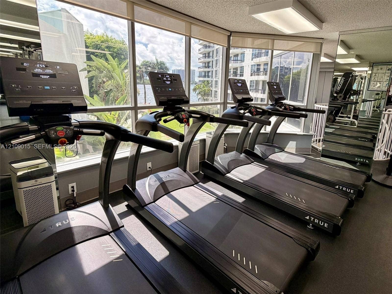 3530 Mystic Pointe Drive, #1709, Aventura, FL 33180 Fitness center featuring floor-to-ceiling windows, mirrored walls, and multiple professional-grade treadmills
