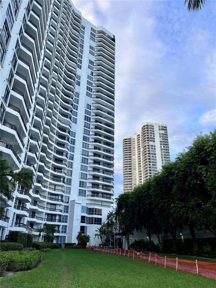 3530 Mystic Pointe Drive, #1709, Aventura, FL 33180 High-rise residential exterior featuring expansive private balconies, white facade, and lush surrounding green space