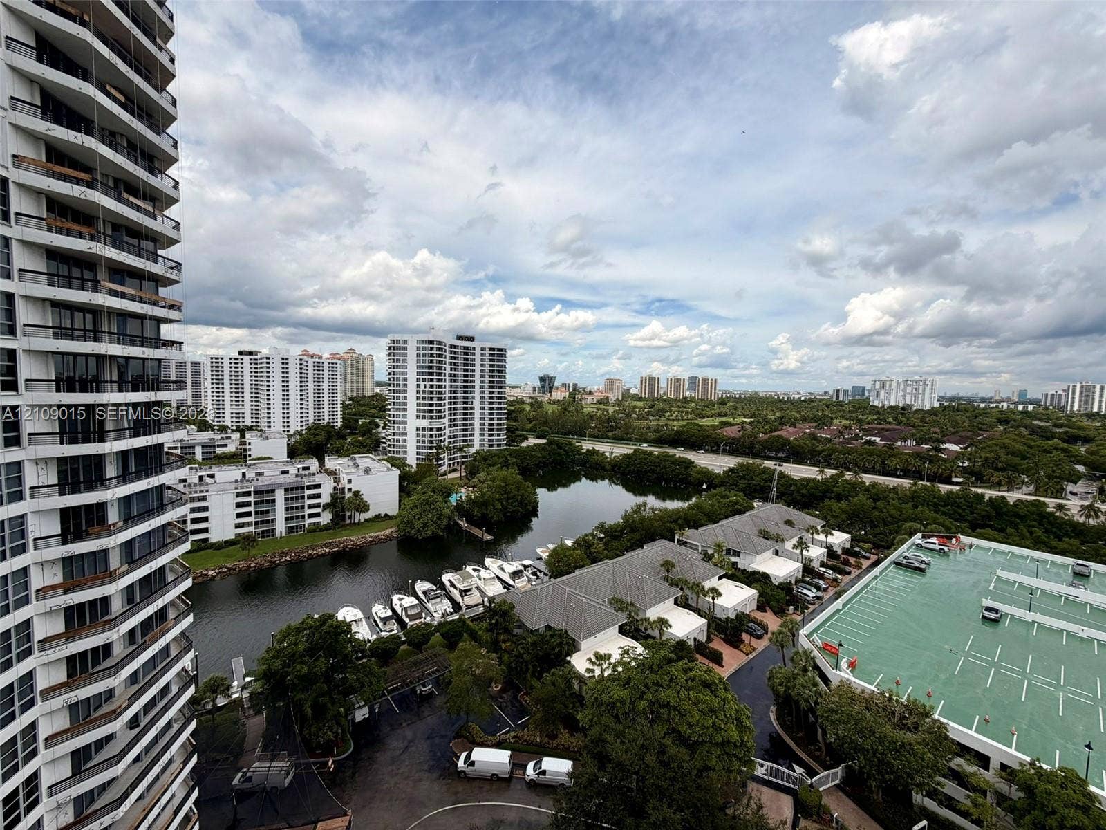 3530 Mystic Pointe Drive, #1709, Aventura, FL 33180 High-rise exterior featuring stacked cantilevered balconies, overlooking a waterway with private boat slips and surrounding residential infrastructure