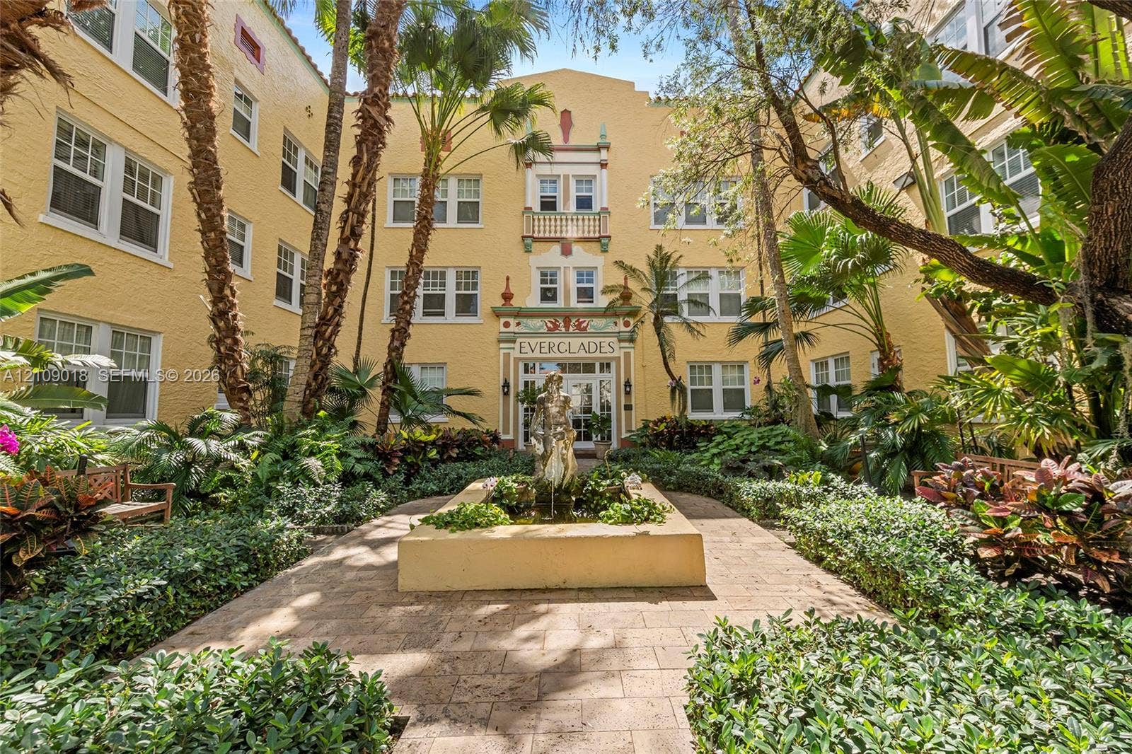 536 14th Street, #305, Miami Beach, Miami Beach, FL 33139 Stucco exterior featuring decorative masonry accents, a central courtyard fountain, multi-pane windows, and paved walkways surrounded by lush mature landscaping