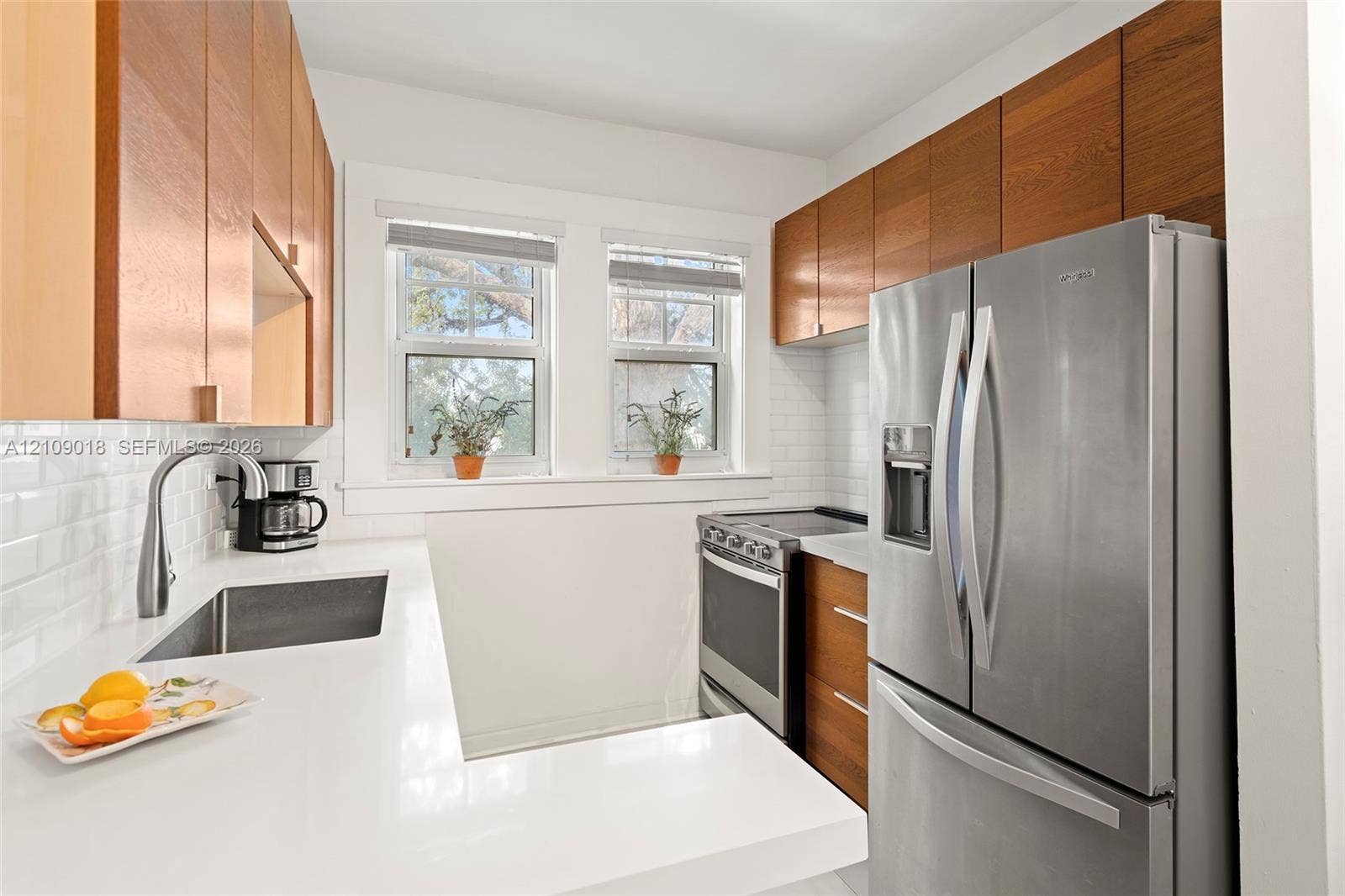536 14th Street, #305, Miami Beach, Miami Beach, FL 33139 Kitchen featuring wood-finish cabinetry, white solid-surface countertops, subway tile backsplash, stainless steel appliances, and a stainless steel undermount sink with a gooseneck faucet