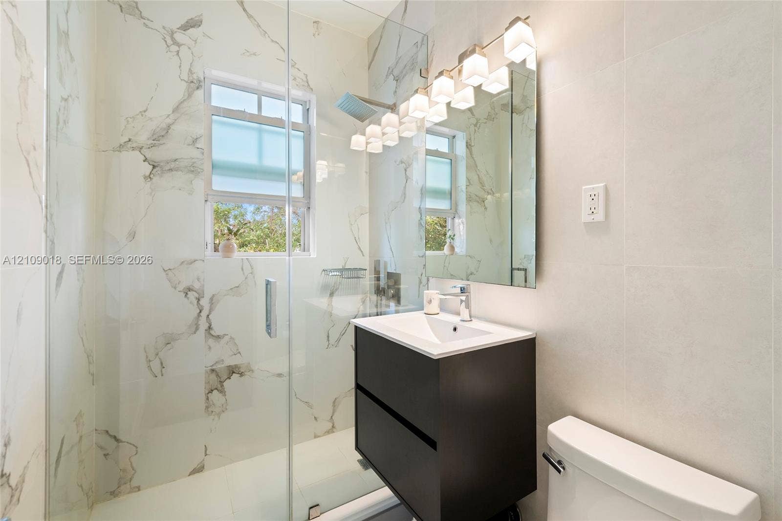 536 14th Street, #305, Miami Beach, Miami Beach, FL 33139 Walk-in shower with floor-to-ceiling large-format veined tile, wall-mounted vanity, multi-bulb vanity lighting, and rectangular undermount sink