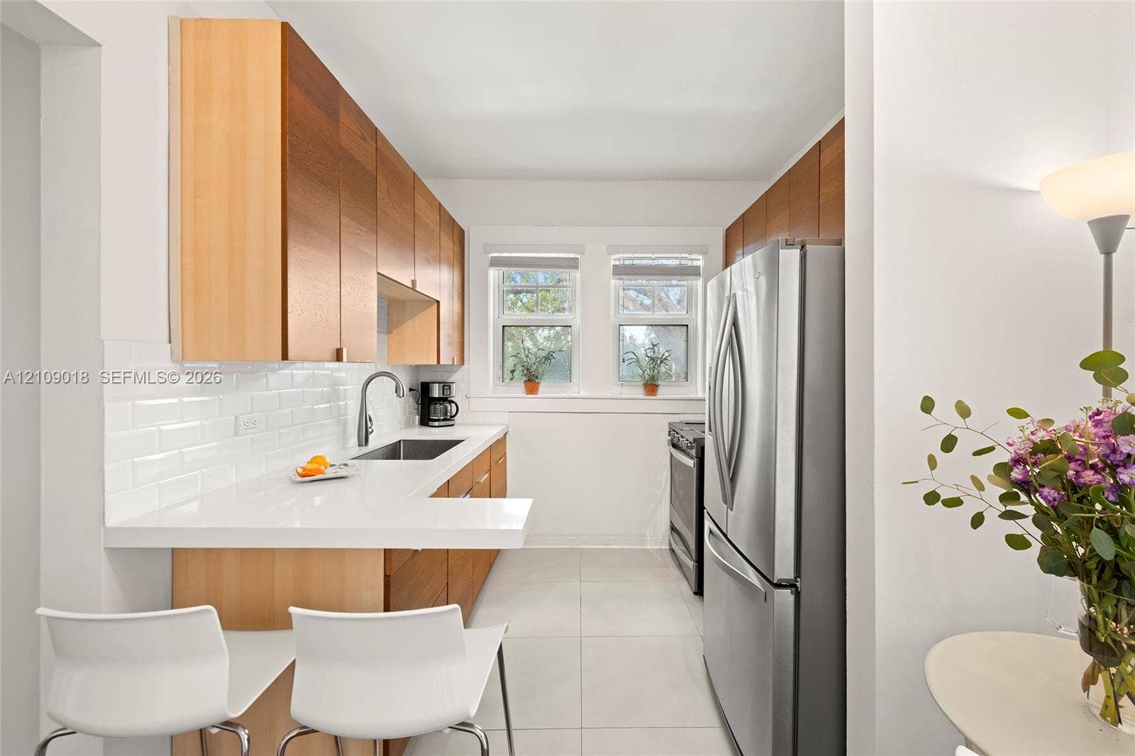 536 14th Street, #305, Miami Beach, Miami Beach, FL 33139 Kitchen featuring wood-finish cabinetry, white subway tile backsplash, solid-surface countertops with a breakfast bar, and stainless steel appliances