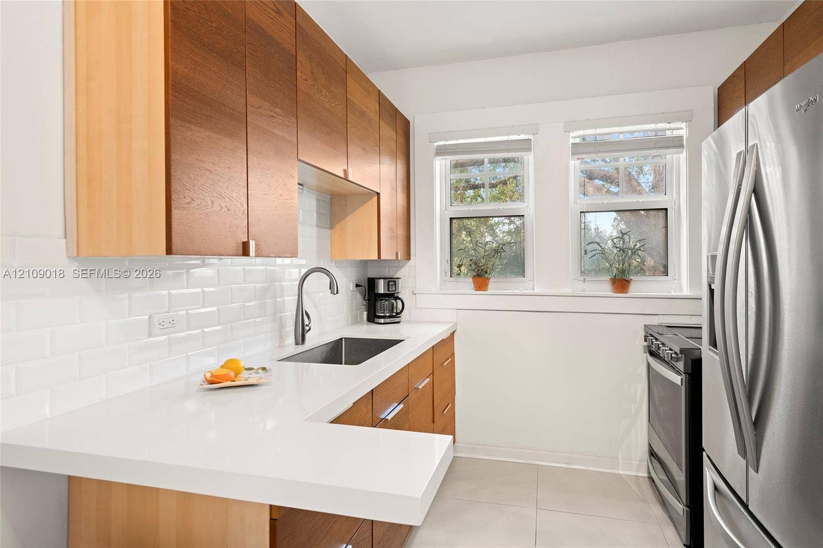 536 14th Street, #305, Miami Beach, Miami Beach, FL 33139 Kitchen featuring natural wood-finish cabinetry, white solid-surface countertops, white subway tile backsplash, stainless steel sink with gooseneck faucet, and stainless steel appliances