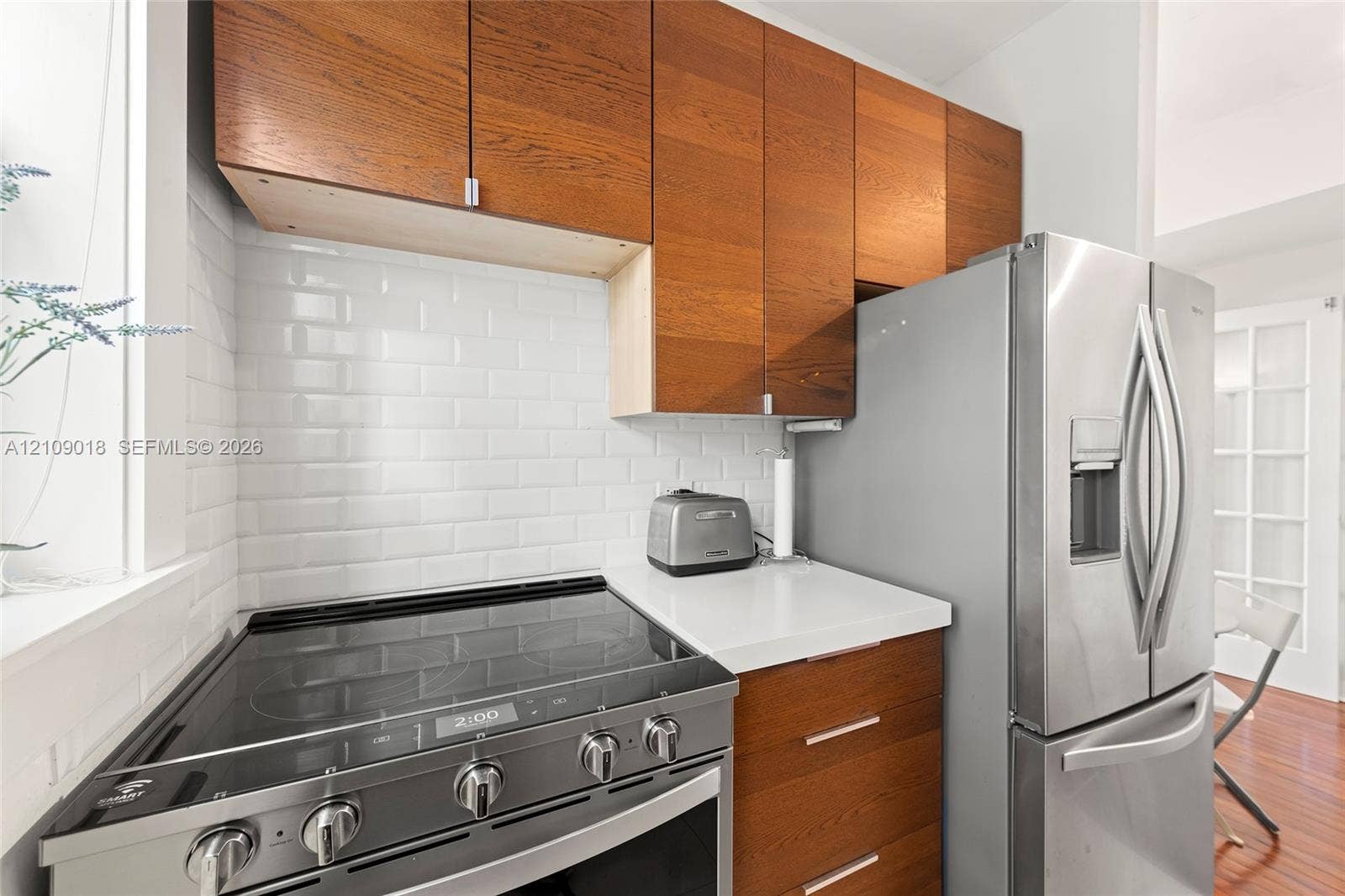 536 14th Street, #305, Miami Beach, Miami Beach, FL 33139 Kitchen featuring wood-finish cabinetry, white solid-surface countertops, a white subway tile backsplash, and stainless steel appliances