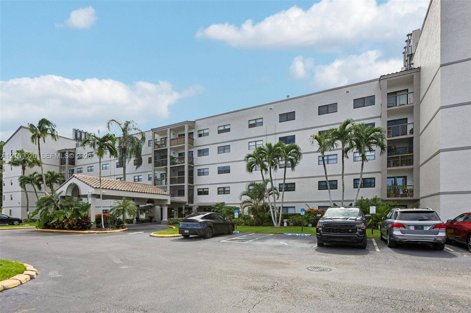 701 NW 19th Street, #300, Fort Lauderdale, FL 33311 Multi-story stucco exterior featuring a covered porte-cochre with tile roofing, private recessed balconies, and mature palm landscaping