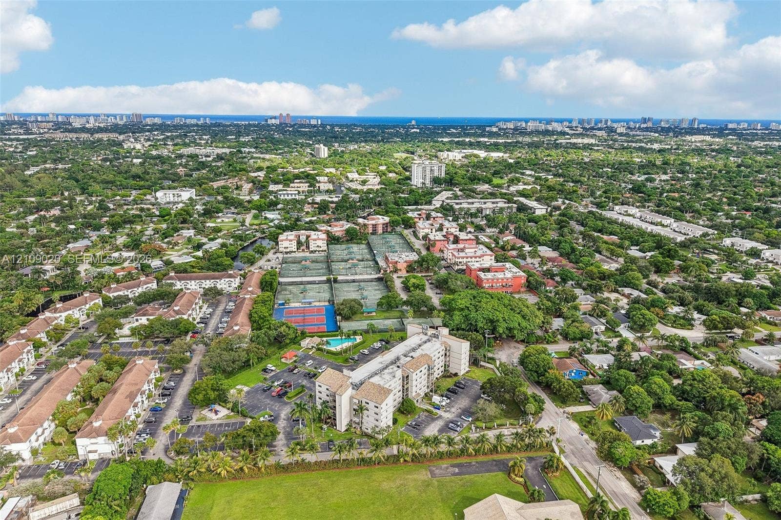 701 NW 19th Street, #300, Fort Lauderdale, FL 33311 Aerial perspective of a multi-building residential complex featuring tennis courts, a swimming pool, surface parking, and landscaped grounds