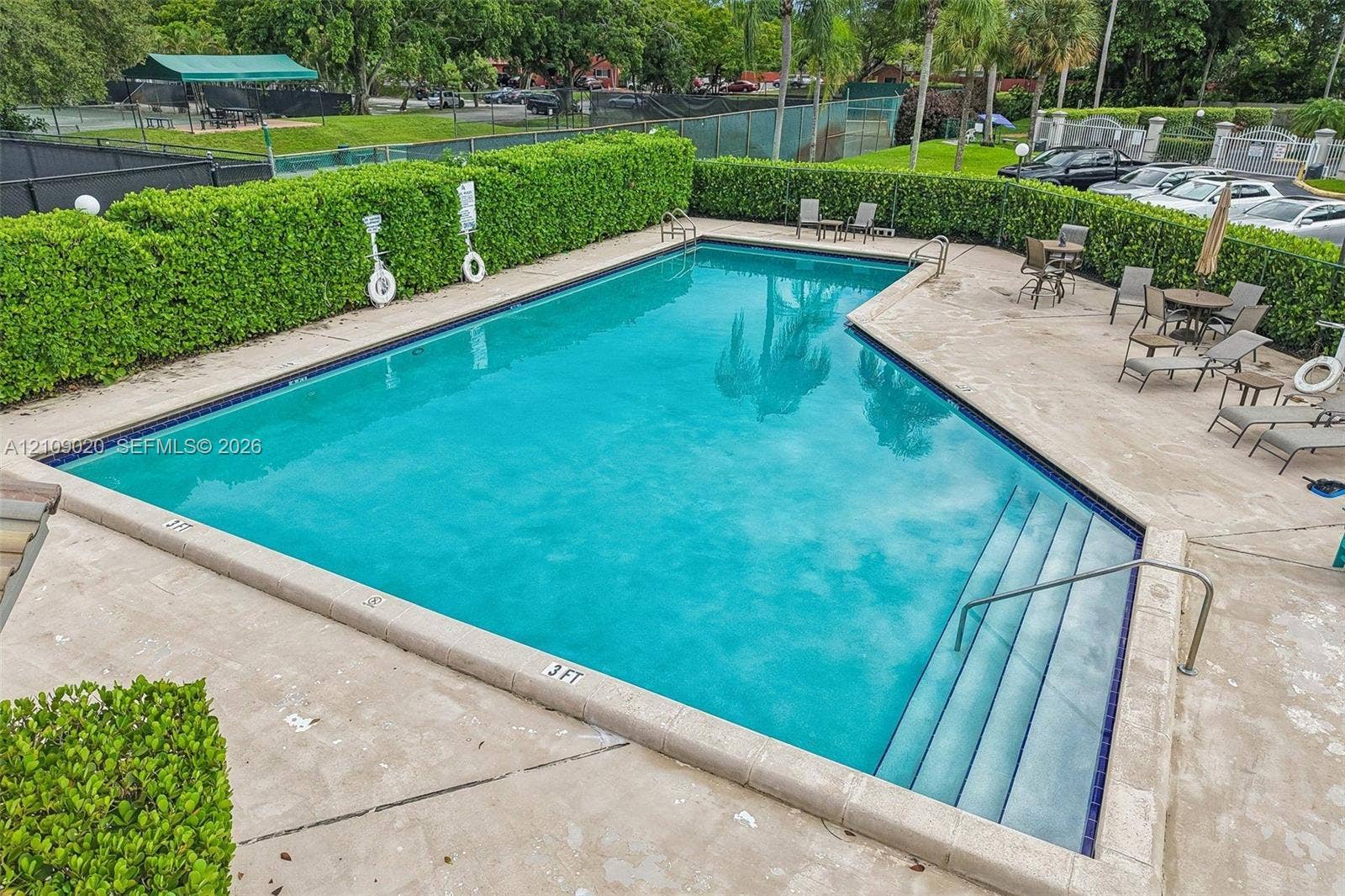 701 NW 19th Street, #300, Fort Lauderdale, FL 33311 In-ground swimming pool with integrated stair entry, light-colored concrete decking, and perimeter privacy hedges