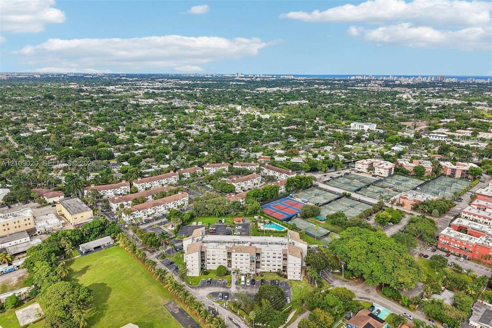 701 NW 19th Street, #300, Fort Lauderdale, FL 33311 Aerial perspective of a multi-story residential building featuring an on-site swimming pool and hard-surfaced tennis courts